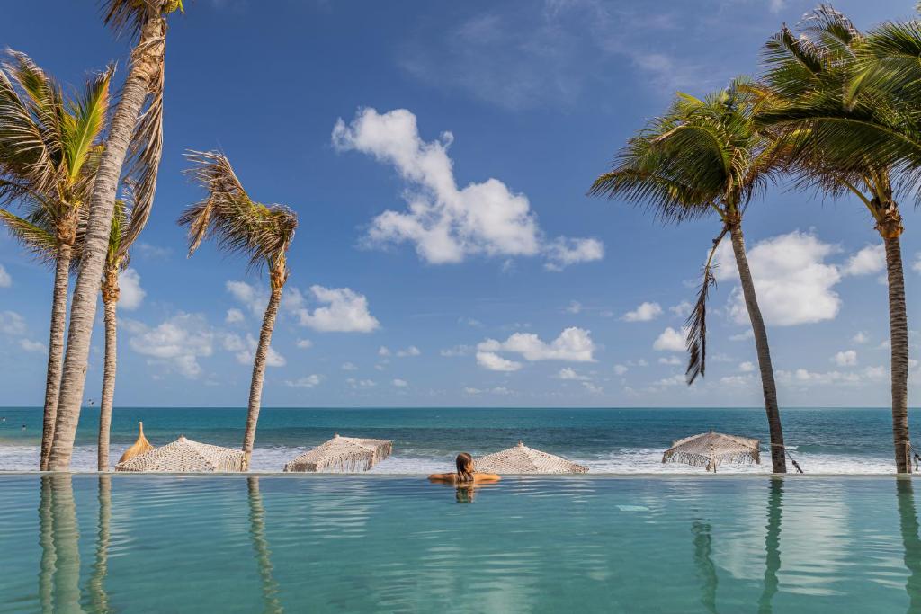a person in a pool on a beach with palm trees at Saline Taíba Boutique Beach Hotel in Taíba