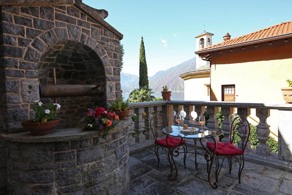 un patio in pietra con tavolo e sedie sul balcone. di Palazzo Del Vicerè a Lezzeno