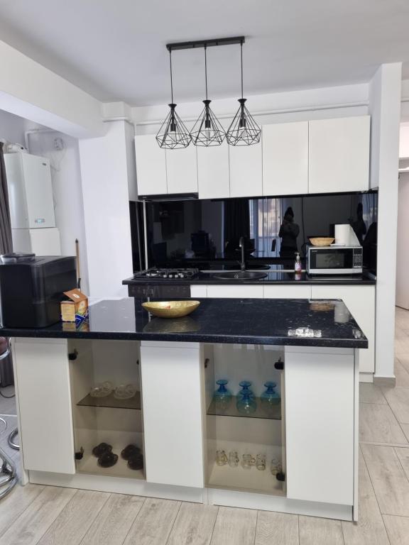 a kitchen with white cabinets and a black counter top at Sweet Home in Iaşi