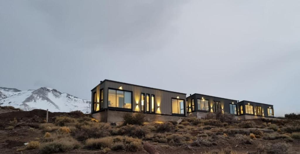 a house on a hill with mountains in the background at Cabañas de Montaña Armonías Lodge in Los Molles