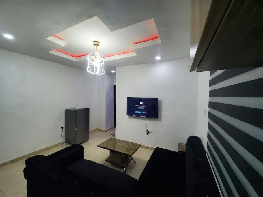 a living room with a black couch and a tv at DINERO DIAMOND - ONE BED APARTMENT in Lagos