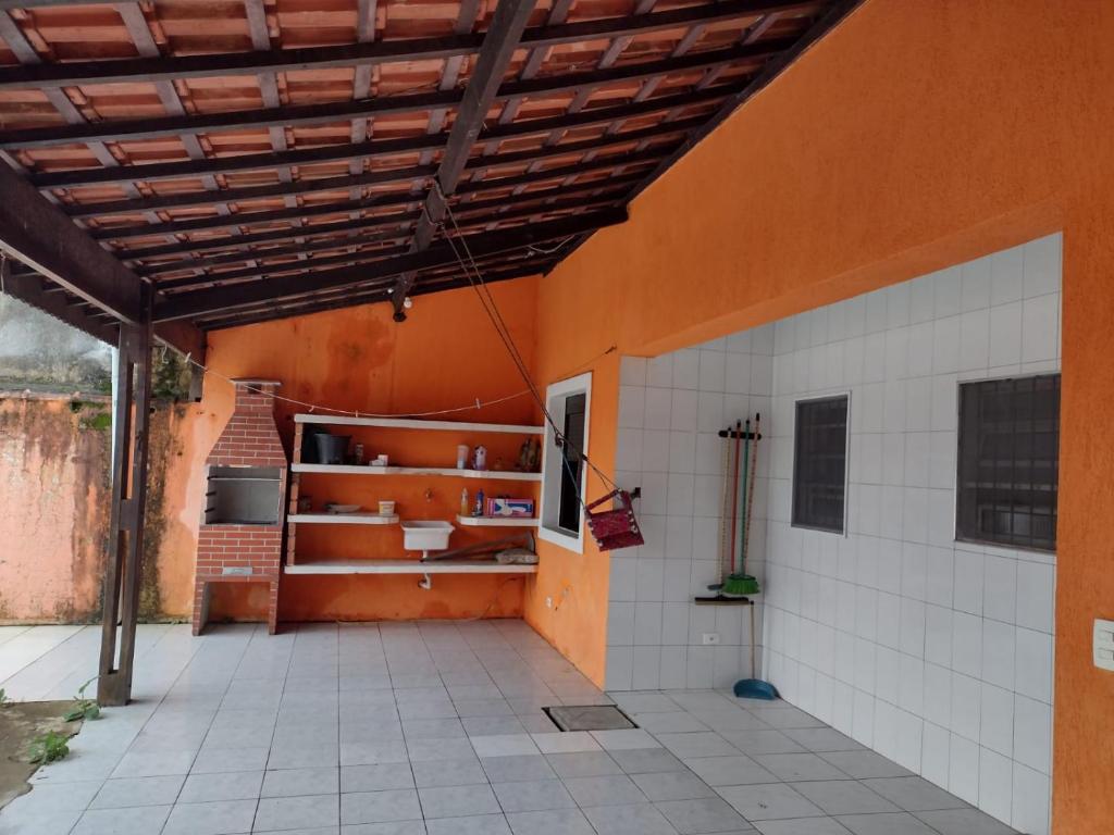 a room with an orange wall and white tiles at Casa Mongaguá Plataforma in Mongaguá