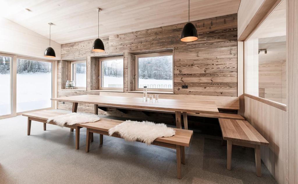 une salle à manger avec une table et des bancs en bois dans l'établissement Ferienhaus Schihütte Mellau, à Mellau