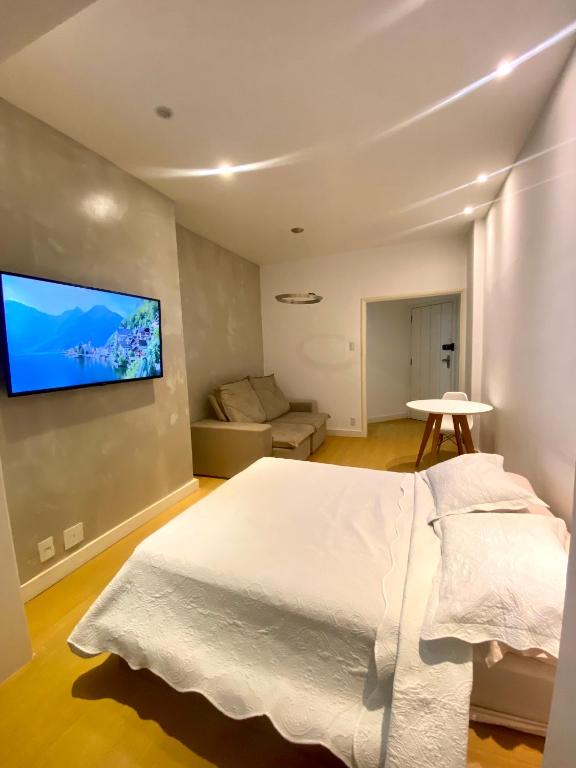 a bedroom with a white bed and a flat screen tv at Apartamento Encantador Leme - Prédio na Orla in Rio de Janeiro