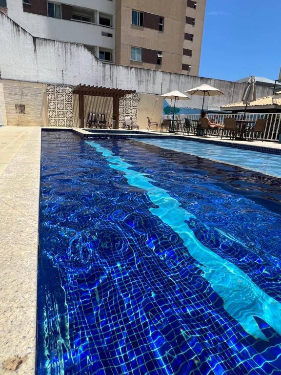 una gran piscina con azulejos azules. en Apartamento - 3 Quartos climatizados - By BellaEstadia, en Aracaju