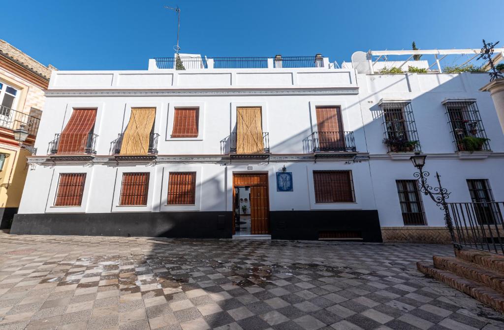 um edifício branco com portas e janelas vermelhas em Apartamentos Cruz de San Andrés em Sevilha