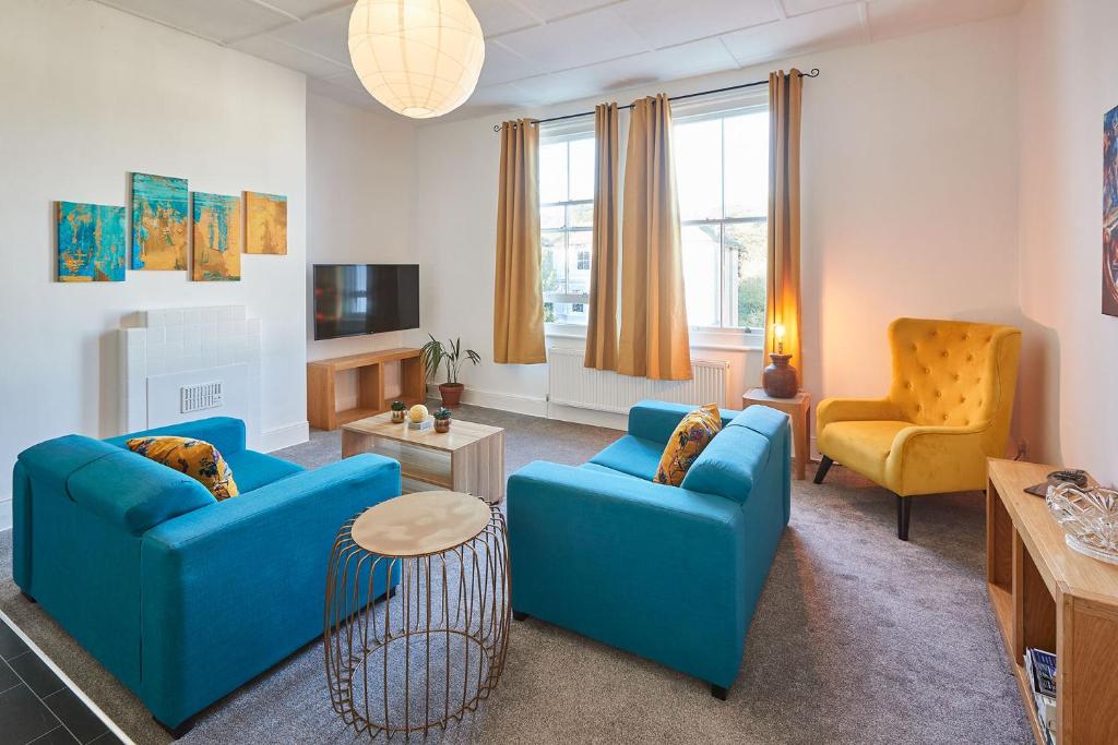 a living room with two blue couches and a tv at Beautiful Sea View Apartment in St Leonards on Sea in St. Leonards