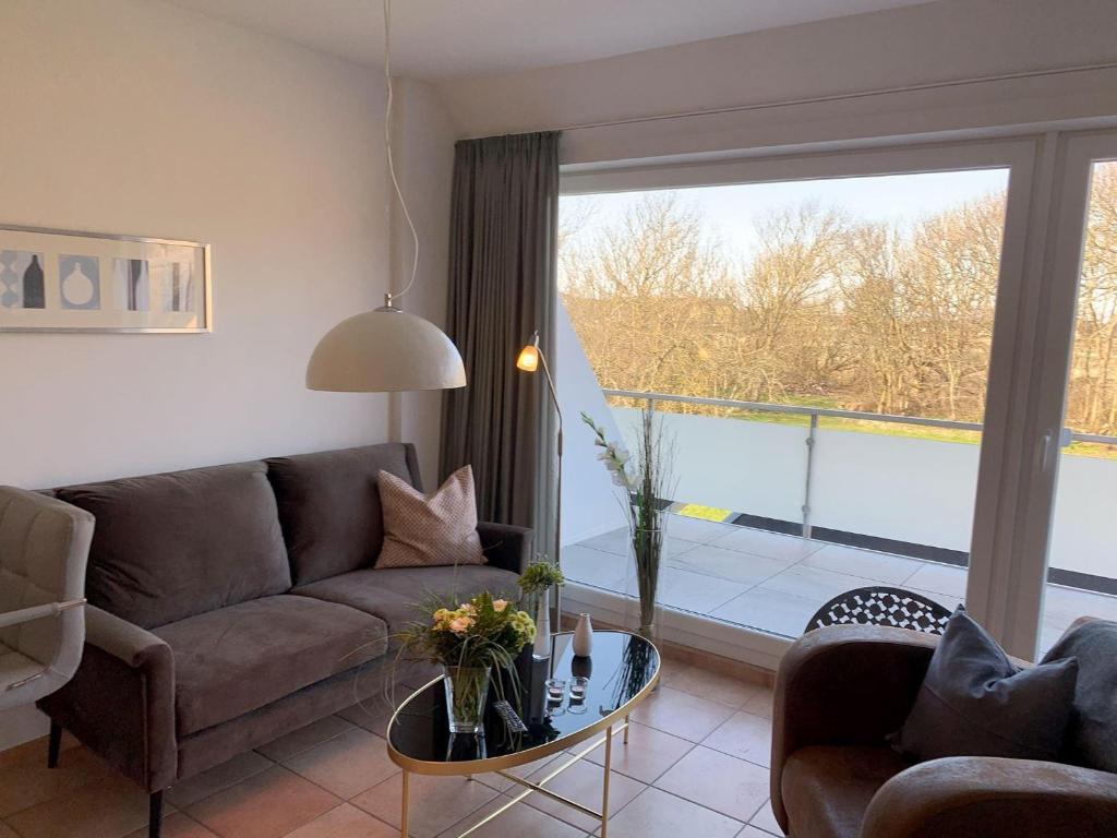 a living room with a couch and a large window at Luna-Wohnung-12 in Sankt Peter-Ording