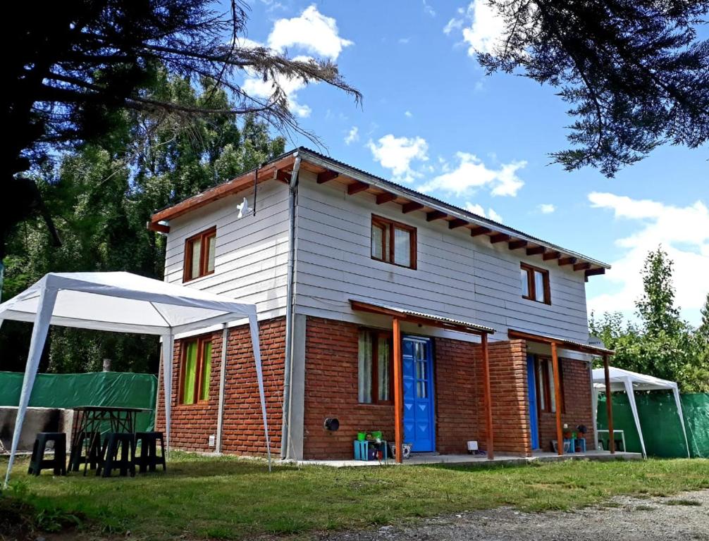 una casa con una tienda verde delante de ella en Duplex Luna en Lago Puelo