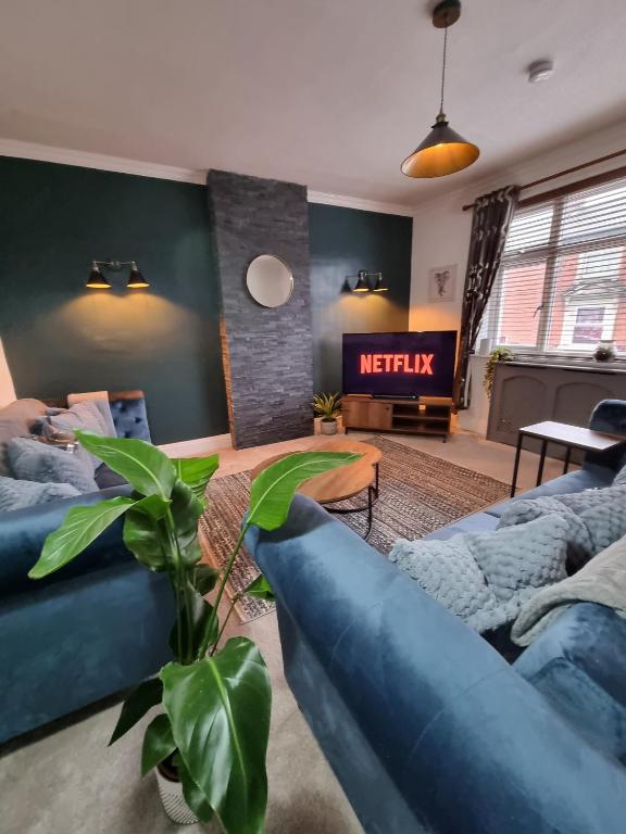 a living room with blue couches and a fireplace at The View Sandbach in Sandbach