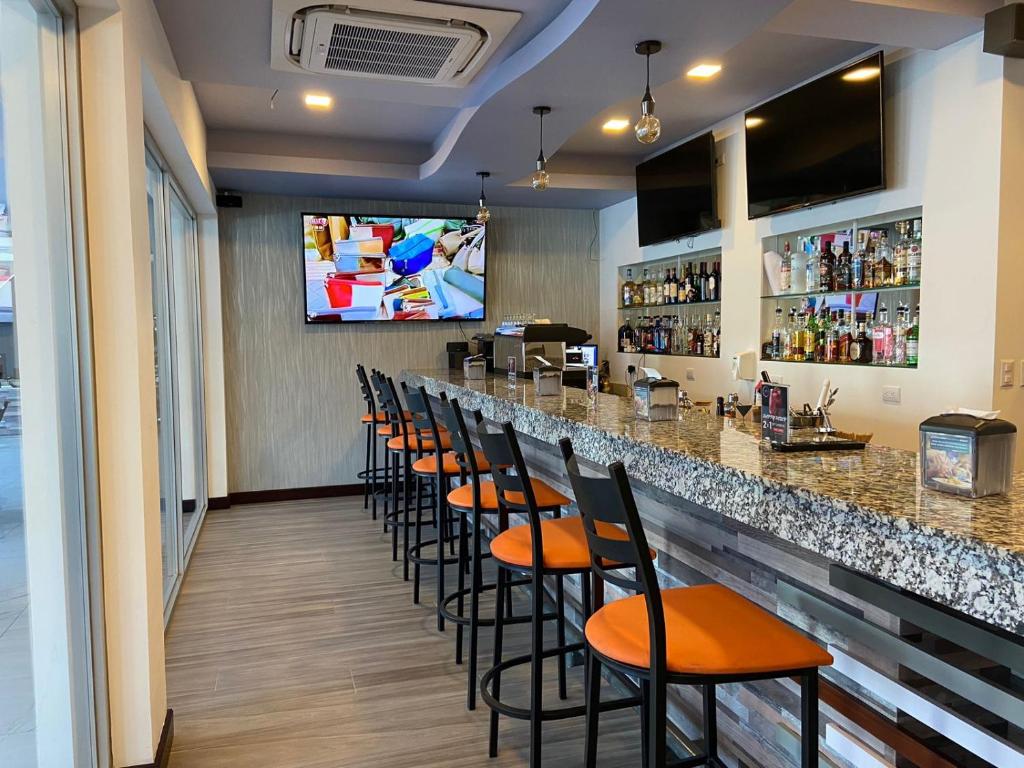 un bar con una fila de taburetes en un restaurante en Hotel Cayuga en Puntarenas