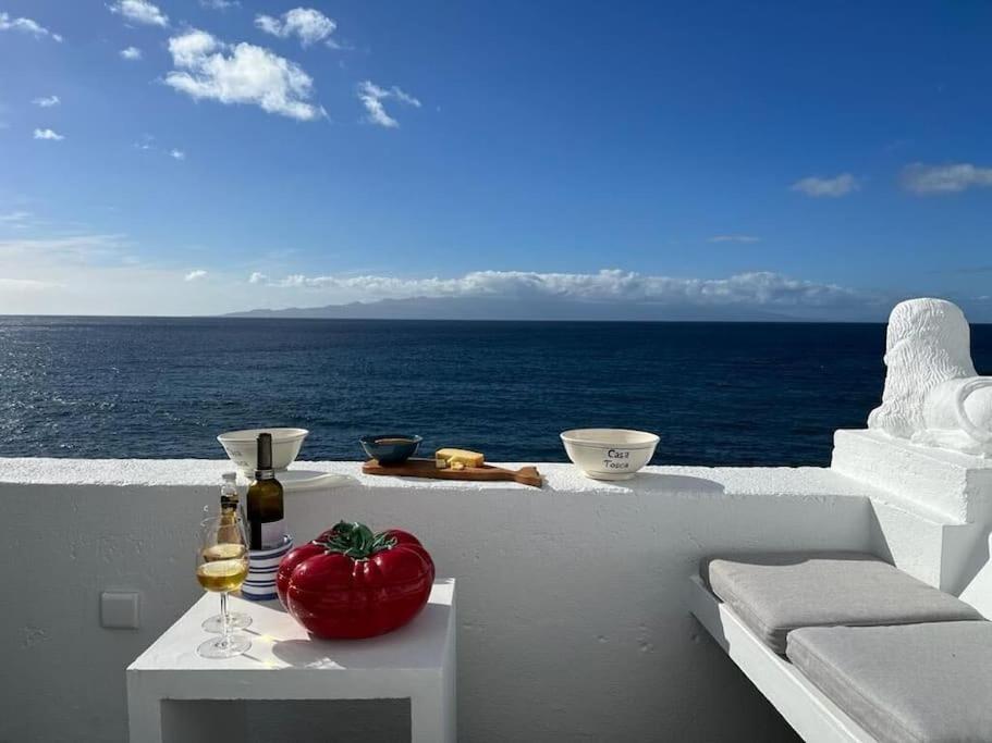 een tafel met een rode tomaat op een balkon met uitzicht op de oceaan bij Casa Tosca in Fajã de São João