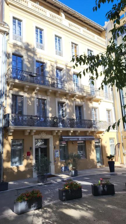 Un grand bâtiment blanc avec balcon se trouve dans une rue. dans l'établissement SQUARE HOTEL, à Nîmes