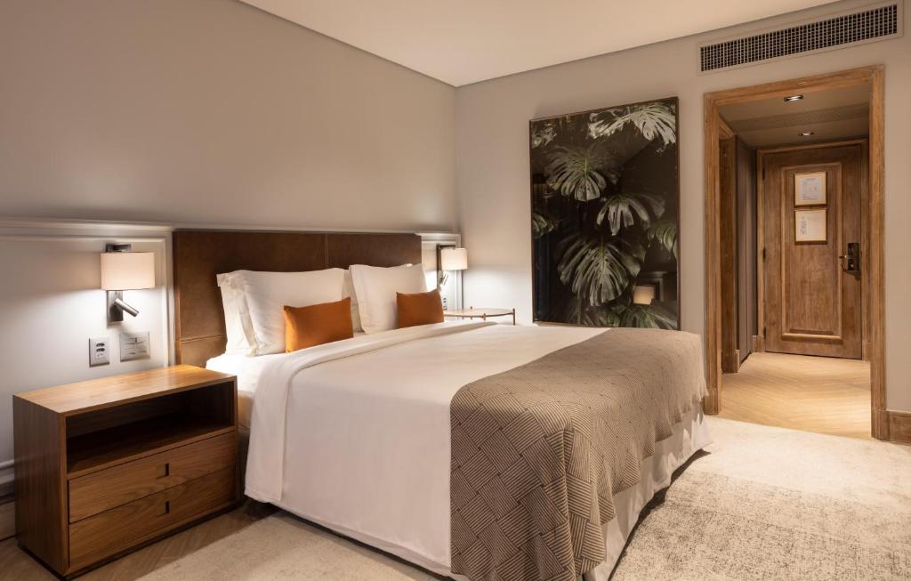 um quarto com uma grande cama branca e uma cabeceira em madeira em L'Hotel PortoBay São Paulo em São Paulo