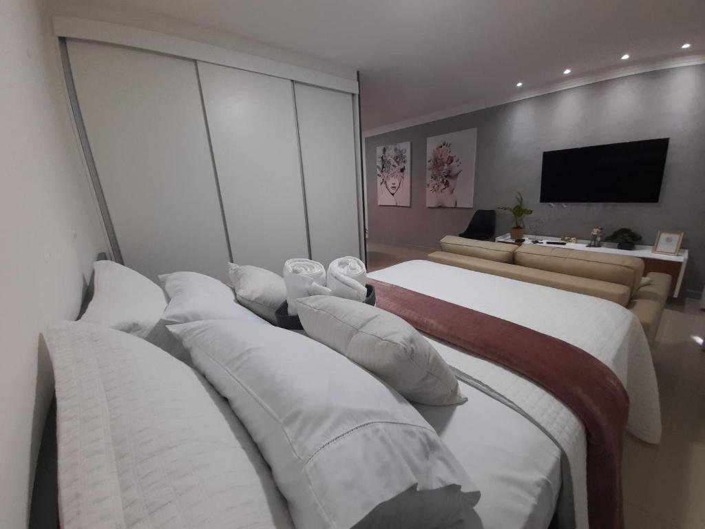 a hotel room with three beds and a television at Studio 1202 Guarulhos Aeroporto in Guarulhos