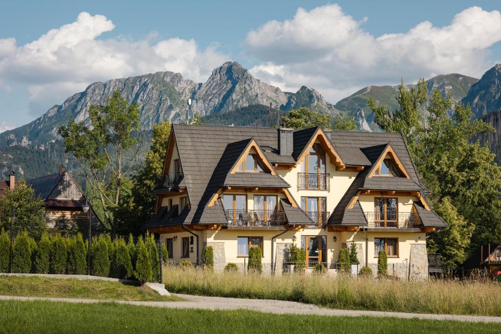 une maison avec des montagnes en arrière-plan dans l'établissement Dworek pod Giewontem, à Kościelisko