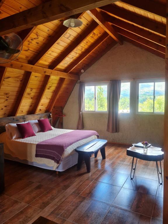 1 dormitorio con cama y techo de madera en La Amarilla Casa de Huéspedes Ruta 40 Montañas en Epuyén