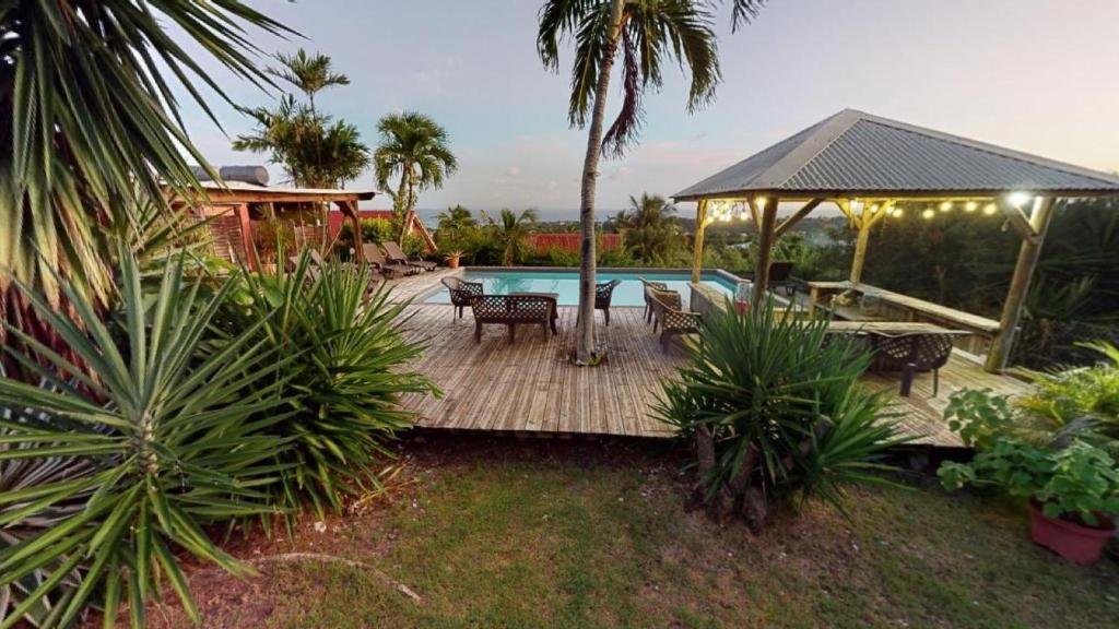 una terraza de madera con sillas y una piscina en Baobab Guadeloupe, en Sainte-Anne