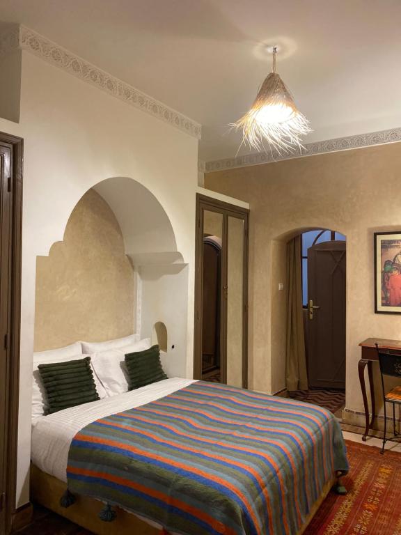 1 dormitorio con 1 cama grande con una manta colorida en Riad au cœur de la médina loué entièrement avec ménage et petit déjeuner compris, en Marrakech