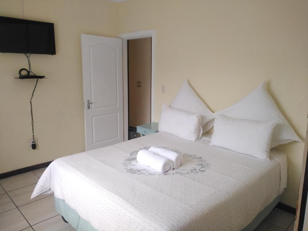 a bedroom with a white bed with two towels on it at The Royal Holiday Home in Port Shepstone