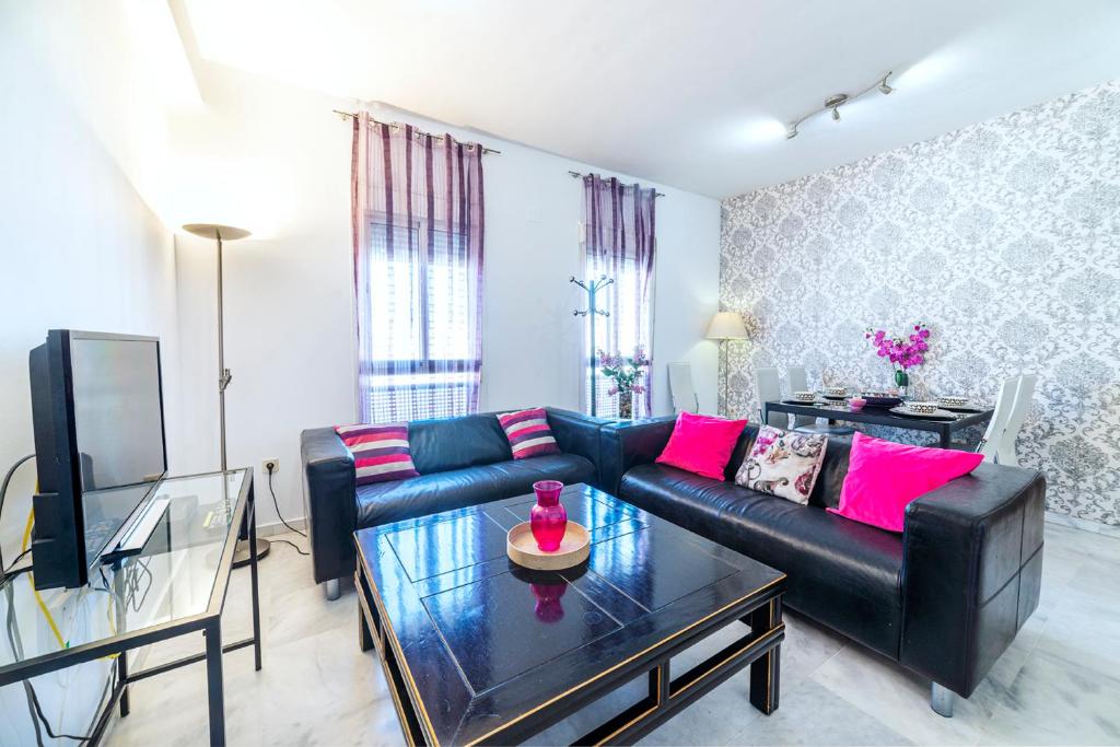 a living room with a black leather couch and a table at Apartamento La Salle in Seville