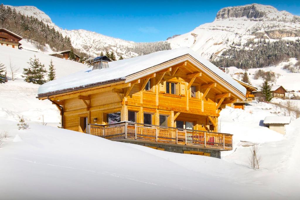 una cabaña de madera en la nieve con nieve en Chalet Le Charmieux - OVO Network, en Le Grand-Bornand