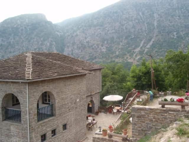 a brick building with a table and chairs in front of a mountain at ΠΑΝΟΡΑΜΑ ΤΣΕΠΕΛΟΒΟΥ in Tsepelovo