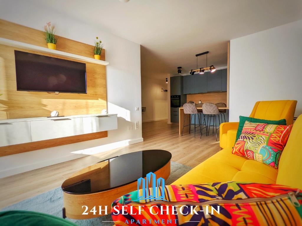 - un salon avec un canapé jaune et une télévision dans l'établissement Cluj Airport Apartment, à Cluj-Napoca