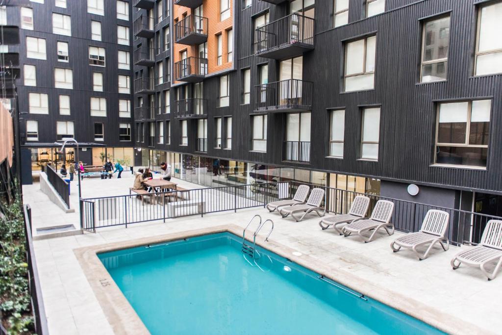 an apartment with a swimming pool in front of a building at LivinnX Santiago in Santiago