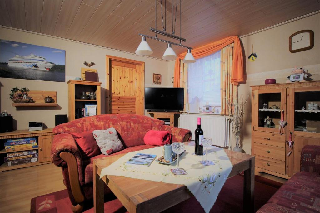 ein Wohnzimmer mit einem roten Sofa und einem Tisch in der Unterkunft Ferienhaus Lüthje in Hochdonn