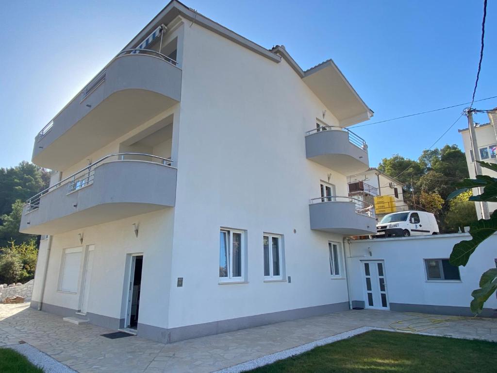 Una casa blanca con balcones en un lateral. en Apartments Antonella, en Trogir