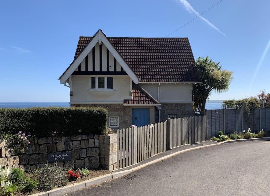 a house with a fence next to a road at Treloyhan Lodge in St Ives