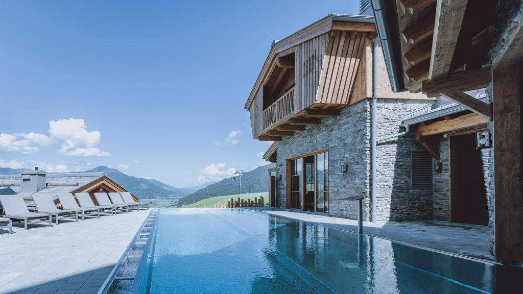 ein Haus mit einem Pool neben einem Gebäude in der Unterkunft Bergdorf Hotel Zaglgut in Kaprun