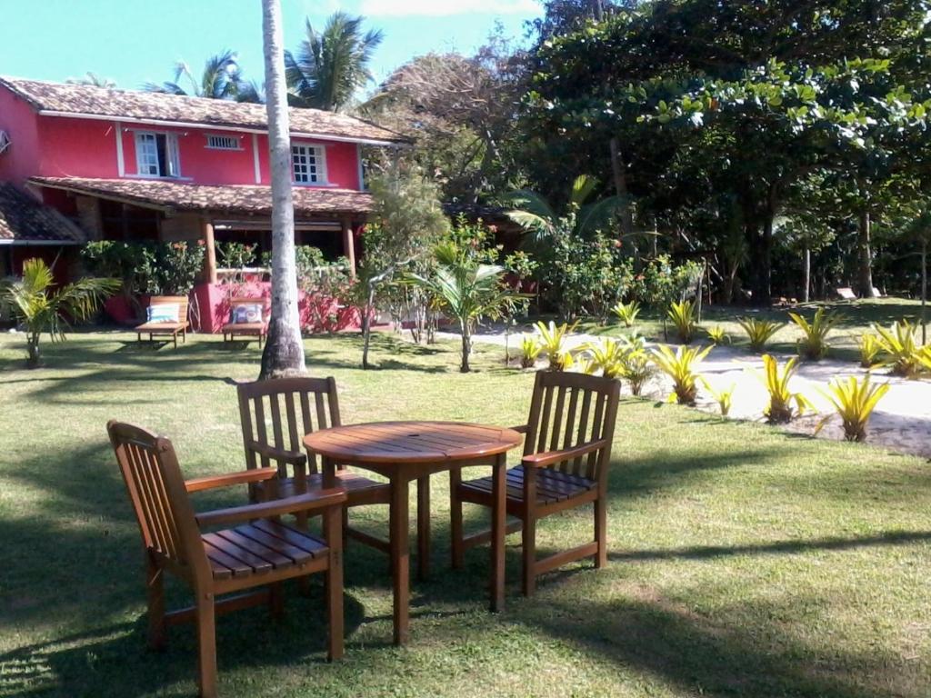 a wooden table and two chairs and a table and a house at Pousada Recanto do Espelho in Praia do Espelho