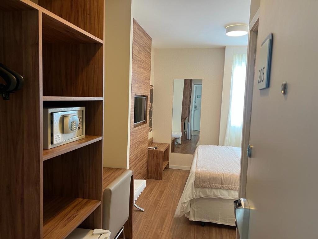 a room with a bedroom with a bed and a television at Quarto plus no Linhares Design Hotel ES in Linhares