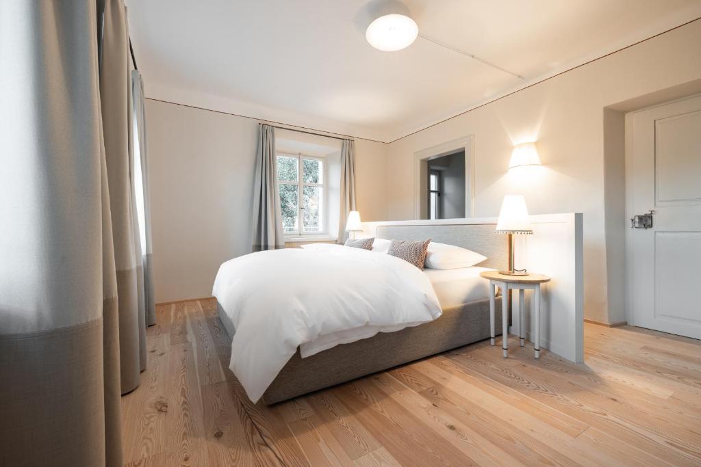 ein Schlafzimmer mit einem großen weißen Bett und einem Tisch in der Unterkunft Smart Suites Kaltern - Apartments am Kalterer See in Kaltern