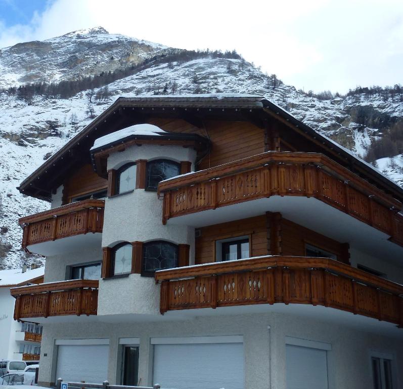ein Gebäude mit Holzbalkonen und einem schneebedeckten Berg in der Unterkunft Apartment Theresli First Floor in Saas-Almagell