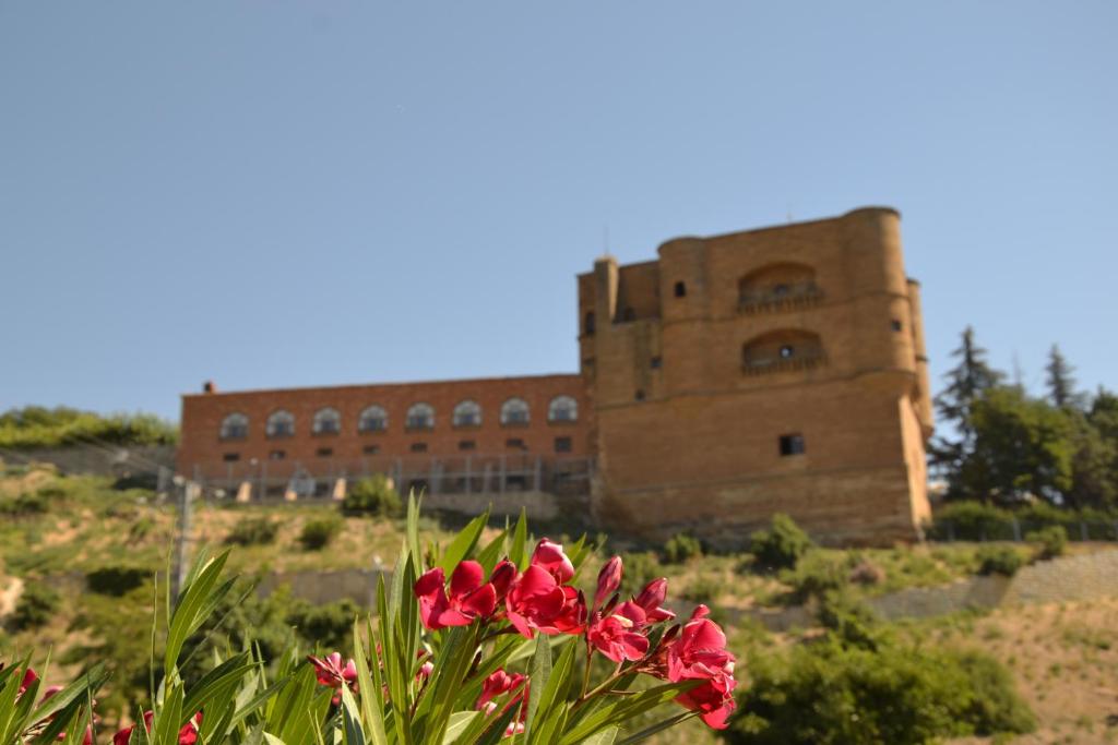 un edificio de fondo con flores rojas en primer plano en Parador de Benavente en Benavente