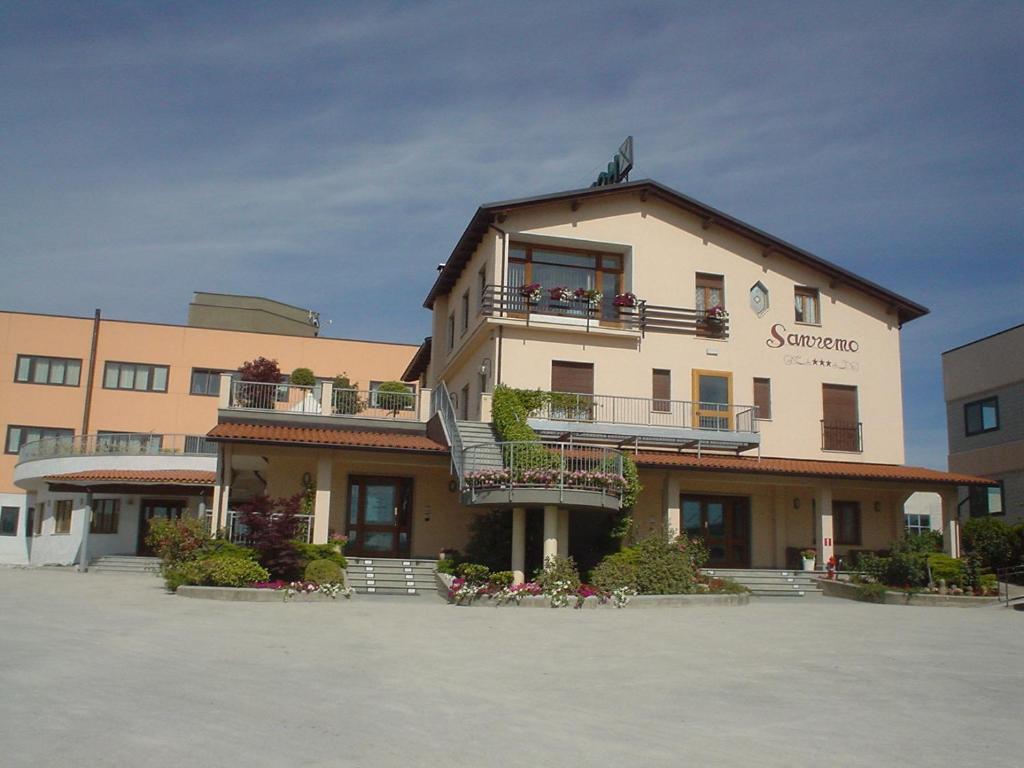 een groot gebouw met balkons en bloemen op een parkeerplaats bij Hotel Sanremo in Ceva
