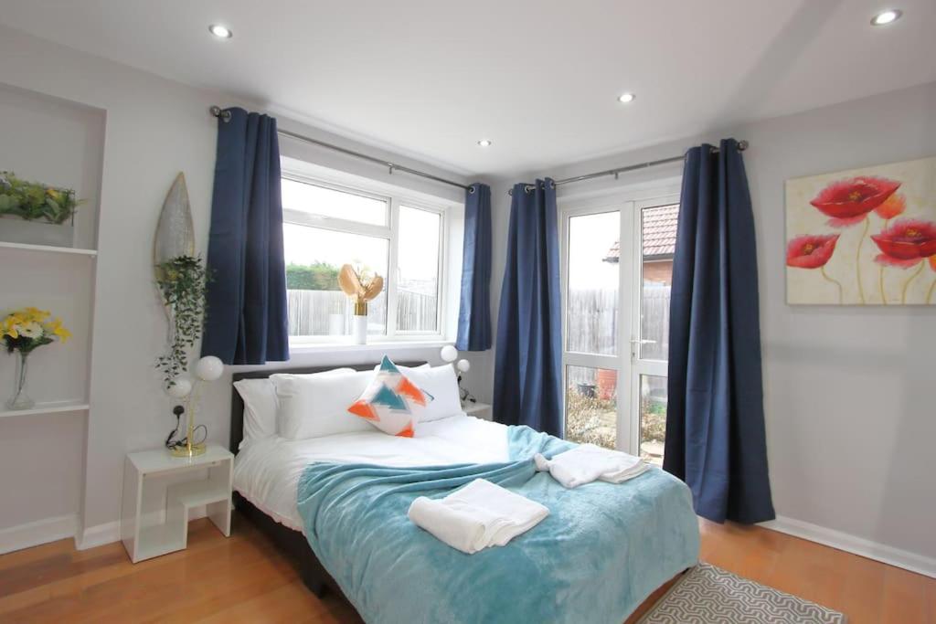 a bedroom with a bed with blue curtains and a window at Stunning 3 Bedroom 2 Bathroom Bungalow by CozyNest in Earley