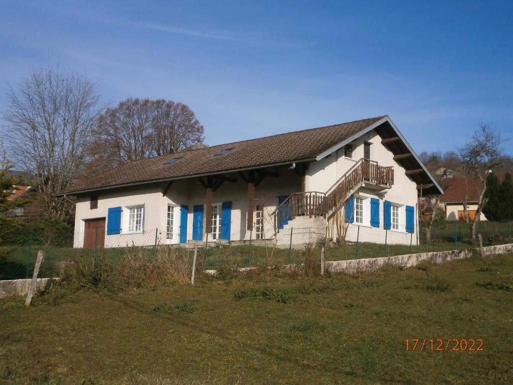 una casa blanca con persianas azules en un campo en Gîte Chez Louve Bleue 3 étoiles-Label Tourisme et Hand, en Le Grand-Abergement