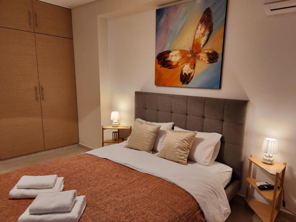 a bedroom with a large bed with a butterfly painting on the wall at Menelaou Cozy Apartment in Athens