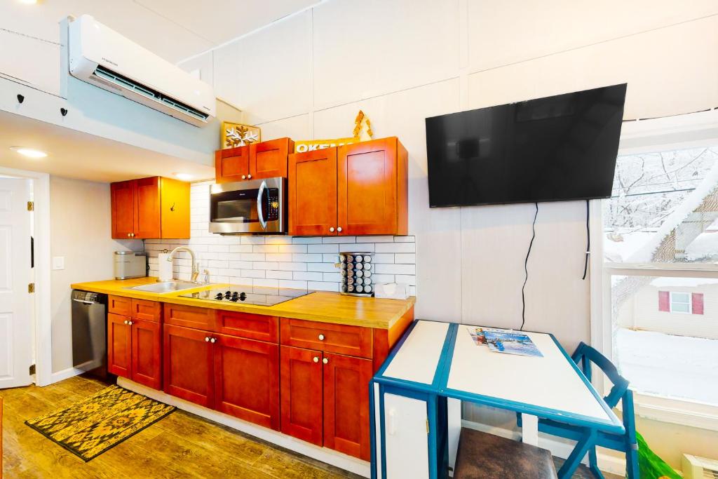 a kitchen with wooden cabinets and a tv on the wall at Tiny Homes on Pleasant in Ludlow