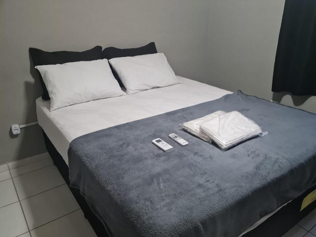 a bed with two remote controls on top of it at 01 APTO em frete ao Shopping Pátio Norte in São-José-do-Ribamar