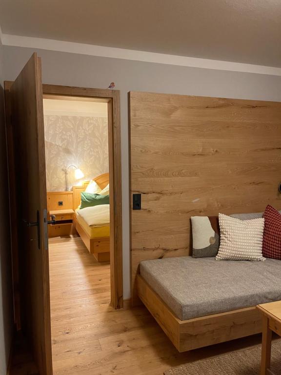 a bedroom with two beds and a wooden wall at Heutaler Hof - Hotel im Naturidyll in Unken