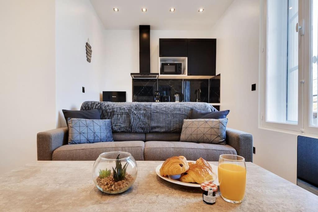 Appartement aux Portes de Paris في سان دوني: غرفة معيشة مع أريكة وطاولة مع طبق من الطعام