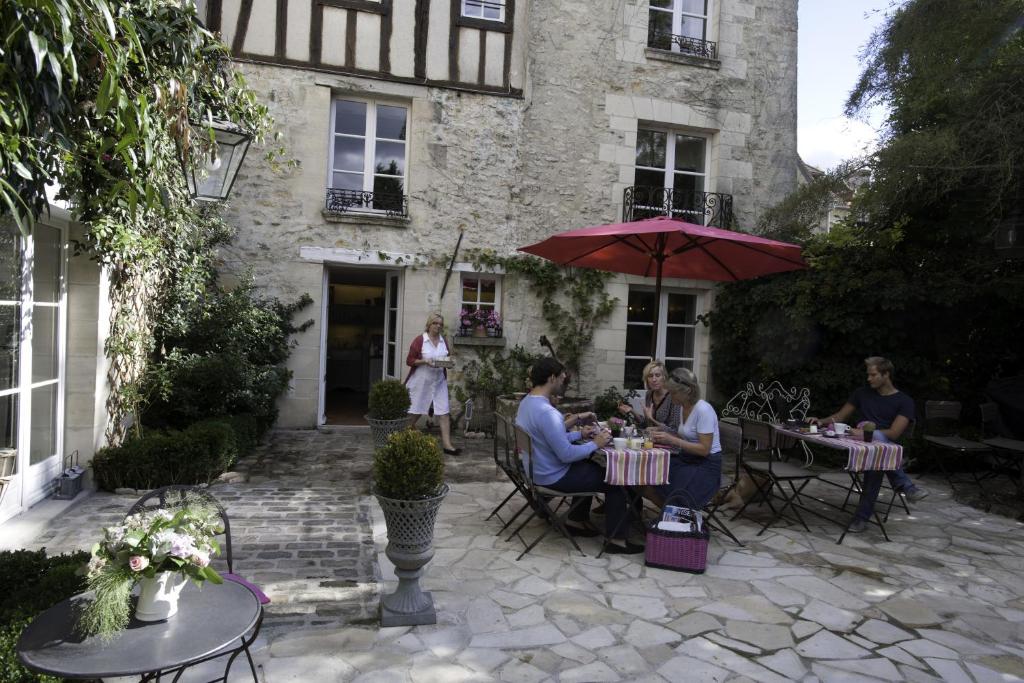 un groupe de personnes assises à des tables devant un bâtiment dans l'établissement Côté Jardin - Chambres d'hôtes, à Senlis