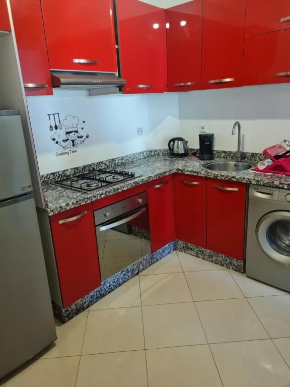 una cucina rossa con lavandino e lavatrice di Marbrerie a Bouskoura
