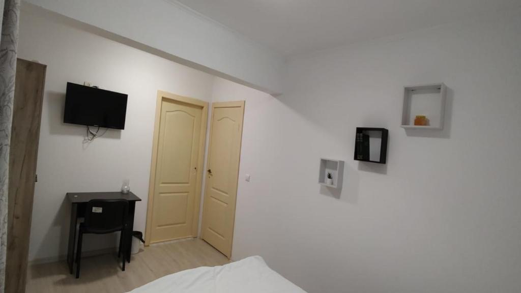 a bedroom with a bed and a television on a wall at Camera de la Bunici - o poarta catre oriunde 