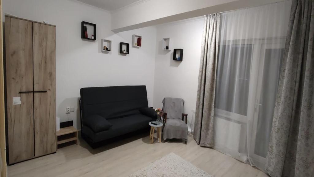 a living room with a black chair and a window at Camera de la Bunici - o poarta catre oriunde 